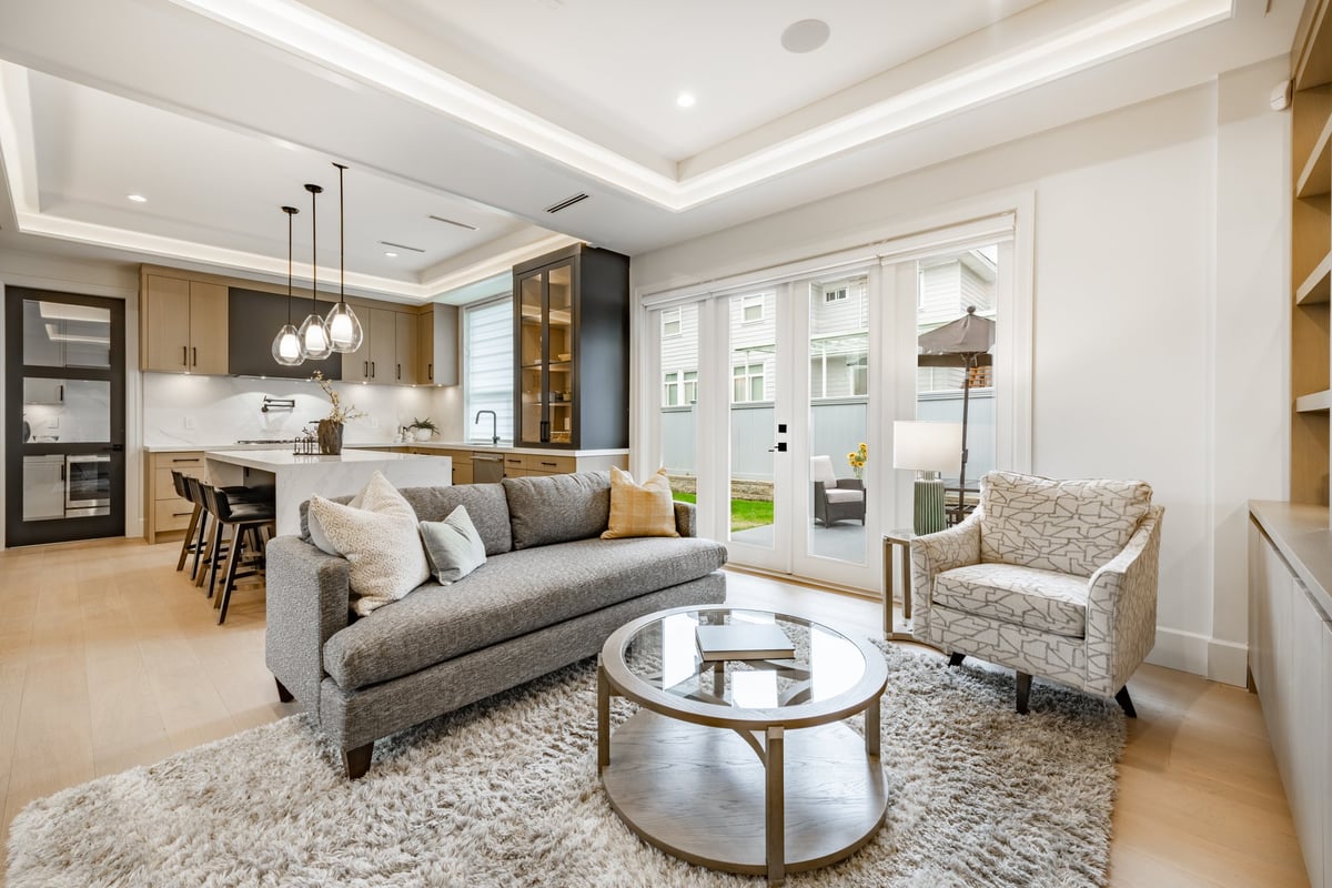 Spacious professionally staged living room in a newly constructed modern home with grey sofa, area rug, built-in cabinetry and recessed lighting